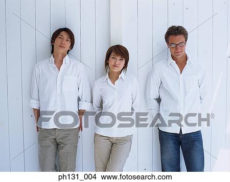 A woman and two men leaning against a wall View Large Photo Image Picture - A woman and two men leaning against a wall. Fotosearch