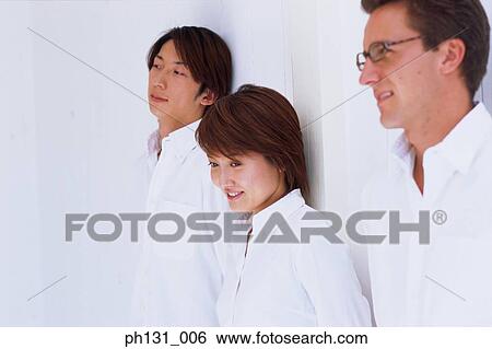 A woman and two men leaning against a wall View Large Photo Image Stock Photograph - A woman and two men leaning against a wall. Fotosearch