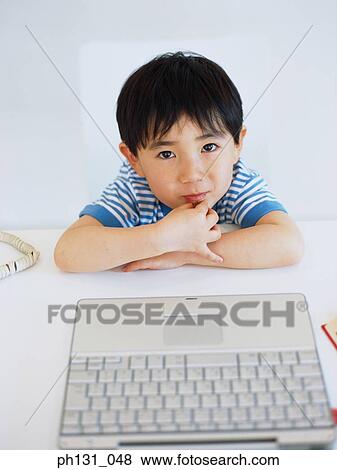 Asian child looking up from a desk View Large Photo Image Stock Photo - Asian child looking up from a desk. Fotosearch