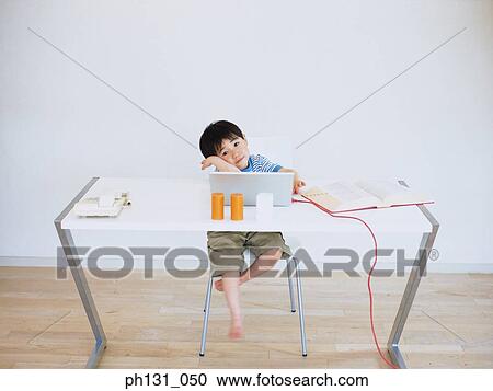Stock Image - Asian child sitting at a desk. Fotosearch