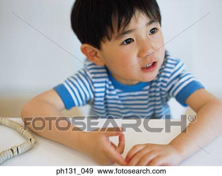 Asian child sitting at a desk View Large Photo Image Stock Photo - Asian child sitting at a desk. Fotosearch