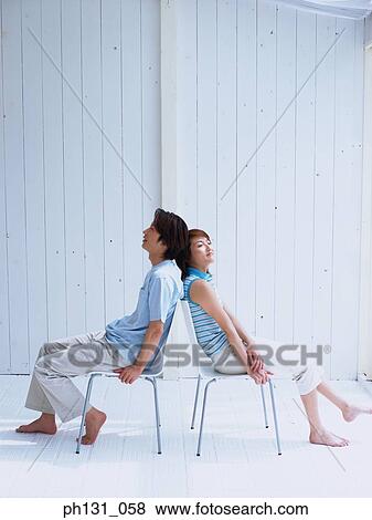 Stock Photo - Asian couple sitting with their backs to each other. Fotosearch