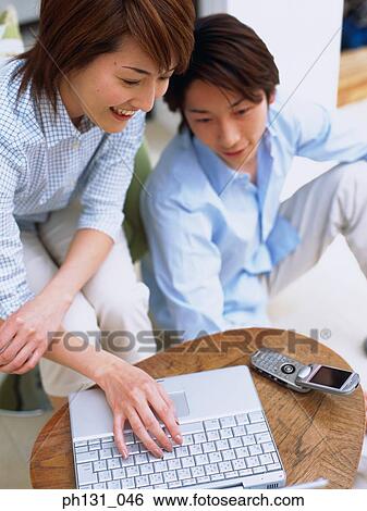 Stock Photograph - Asian couple working together on a laptop. Fotosearch