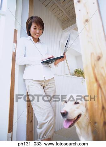 Stock Image - Asian Woman smiling at her dog. Fotosearch