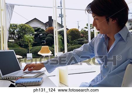 Asian man working on a desk View Large Photo Image Picture - Asian man working on a desk. Fotosearch