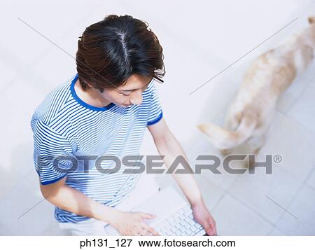 Stock Photo - Asian man working on a laptop. Fotosearch