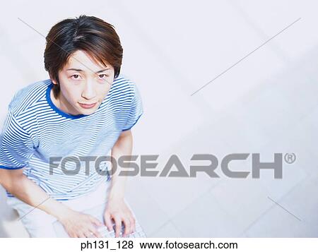 Stock Photo - Asian man working on a laptop. Fotosearch
