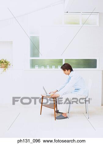 Stock Photograph - Asian man working on a laptop. Fotosearch