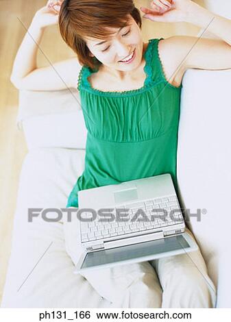 Asian woman stretching on a couch View Large Photo Image Stock Photograph - Asian woman stretching on a couch. Fotosearch