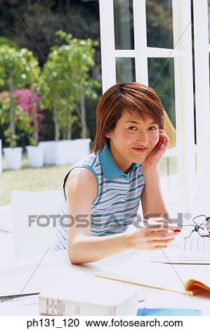 Stock Image - Asian woman working on a desk. Fotosearch