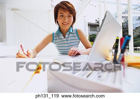 Stock Photo - Asian woman working on a desk. Fotosearch