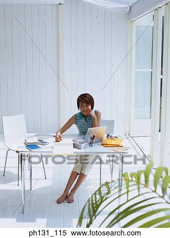 Stock Photography - Asian woman working on a desk. Fotosearch