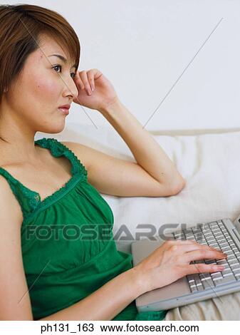 Stock Image - Asian Woman working on a laptop. Fotosearch