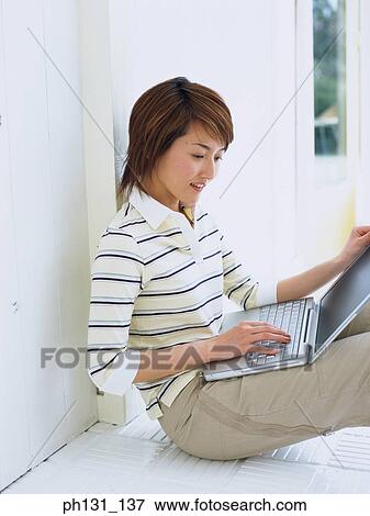 Stock Photo - Asian Woman working on a laptop. Fotosearch