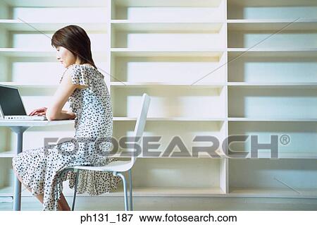 Asian Woman working on a laptop View Large Photo Image Stock Photo - Asian Woman working on a laptop. Fotosearch