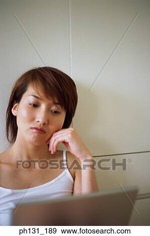 Stock Photo - Asian Woman working on a laptop. Fotosearch