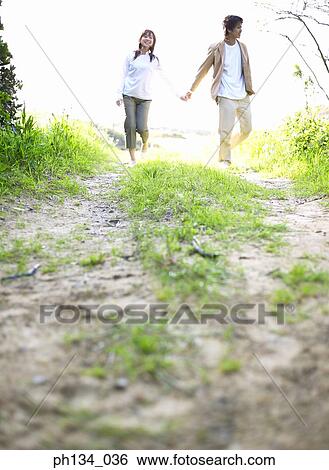 Young couple holding hands and walking View Large Photo Image Stock Photograph - Young couple holding hands and walking. Fotosearch