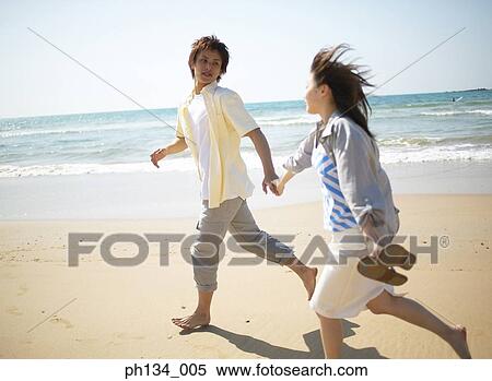 Stock Photography - Young couple running at beach. Fotosearch