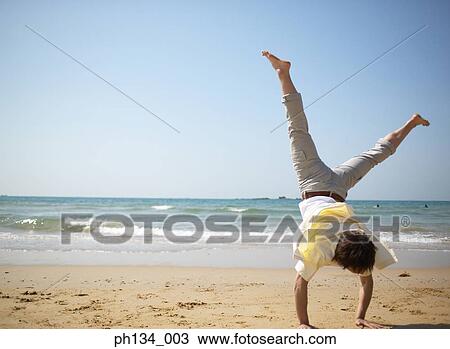 Stock Image - Young man exercising on the beach. Fotosearch