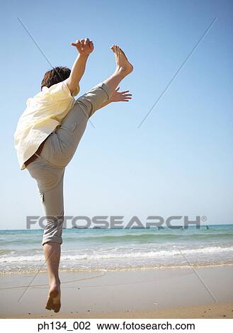 Young man with arms and leg raised View Large Photo Image Stock Image - Young man with arms and leg raised. Fotosearch