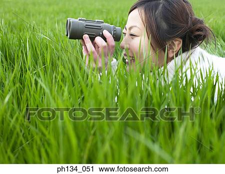 Young woman looking through binoculars View Large Photo Image Stock Image - Young woman looking through binoculars. Fotosearch