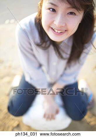 Stock Image - Young woman sitting and smiling. Fotosearch
