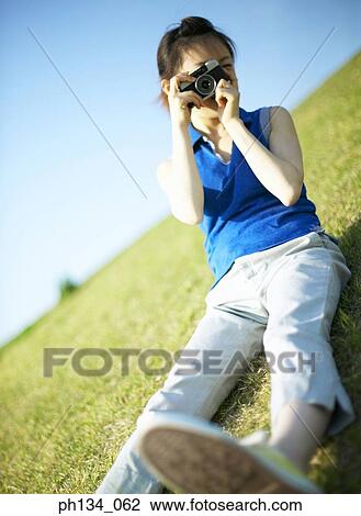 Stock Image - Young woman taking a photograph. Fotosearch