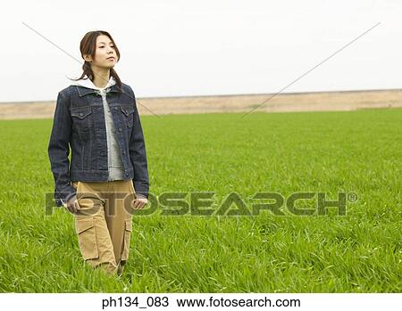 Stock Image - Young woman walking in a field. Fotosearch