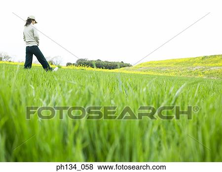 Young woman walking in field View Large Photo Image Stock Photo - Young woman walking in field. Fotosearch