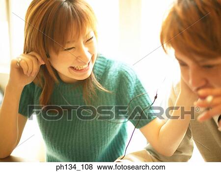 Stock Photo - Young couple sharing a pair of earphones. Fotosearch