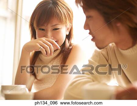 Young couple sitting together View Large Photo Image Stock Photograph - Young couple sitting together. Fotosearch