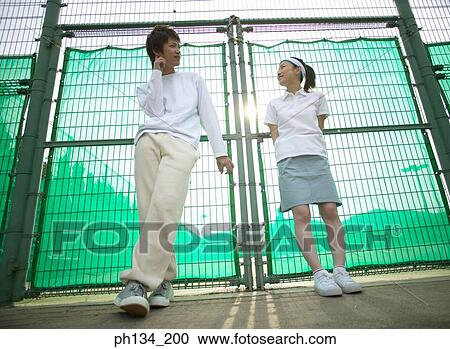Young couple standing together at a tennis court View Large Photo Image Stock Image - Young couple standing together at a tennis court. Fotosearch