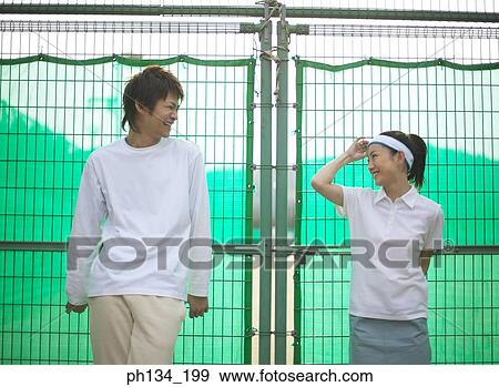 Young couple standing together at a tennis court View Large Photo Image Stock Photo - Young couple standing together at a tennis court. Fotosearch