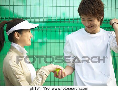 Stock Photograph - Young couple standing together at a tennis court. Fotosearch