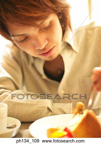 Young man eating View Large Photo Image Stock Photo - Young man eating. Fotosearch