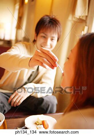 Picture - Young man feeding a young woman. Fotosearch