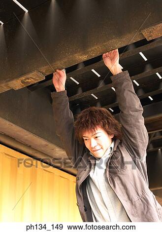 Young man hanging from a beam View Large Photo Image Stock Photo - Young man hanging from a beam. Fotosearch