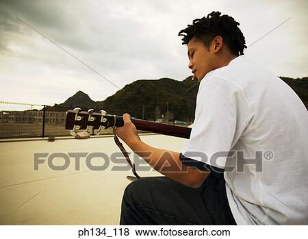 Young man playing guitar View Large Photo Image Stock Photo - Young man playing guitar. Fotosearch