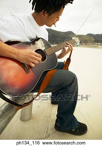 Young man playing guitar View Large Photo Image Stock Photograph - Young man playing guitar. Fotosearch