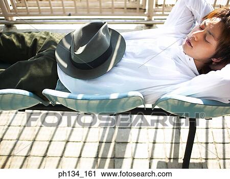 Young man sleeping on chairs View Large Photo Image Stock Image - Young man sleeping on chairs. Fotosearch
