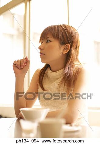 Picture - Young woman sitting at a table. Fotosearch