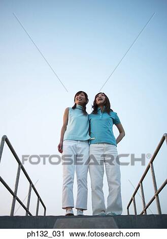 Stock Image - Two young women standing on a platform. Fotosearch