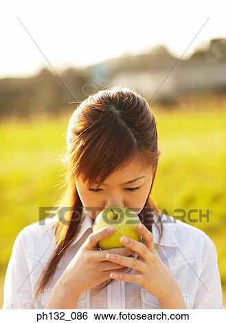 Young woman holding apple View Large Photo Image Stock Photograph - Young woman holding apple. Fotosearch