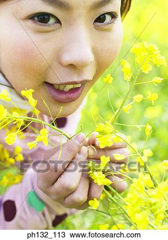 Stock Image - Young woman holding branches of flowers. Fotosearch