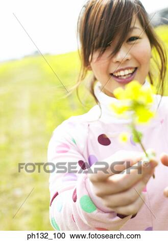 Stock Image - Young woman holding flower. Fotosearch