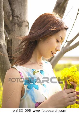 Young woman holding flowers View Large Photo Image Stock Photograph - Young woman holding flowers. Fotosearch