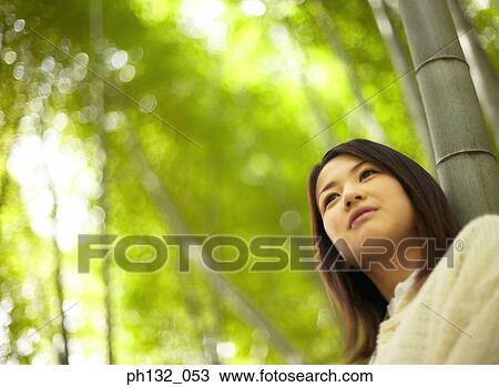 Young woman leaning on tree View Large Photo Image Stock Image - Young woman leaning on tree. Fotosearch