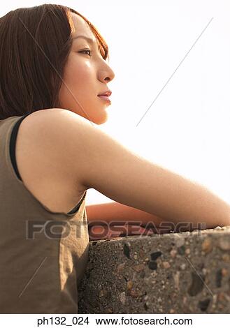 Young woman looking over a ledge View Large Photo Image Picture - Young woman looking over a ledge. Fotosearch