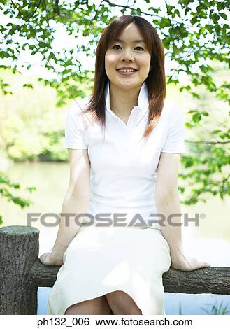 Young woman sitting on a fence View Large Photo Image Stock Photograph - Young woman sitting on a fence. Fotosearch