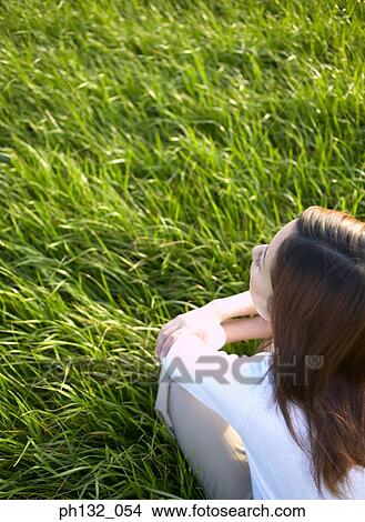 Young woman sitting on grass View Large Photo Image Picture - Young woman sitting on grass. Fotosearch